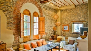 Una habitación rústica con paredes de piedra, muebles de madera y un ventilador de techo.