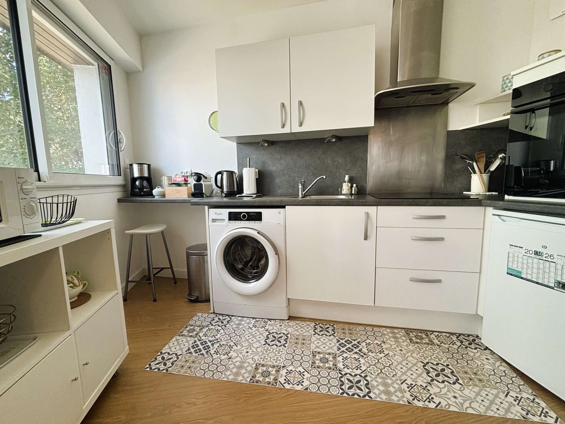 A compact kitchen with a washing machine, a coffee maker, and a sink.