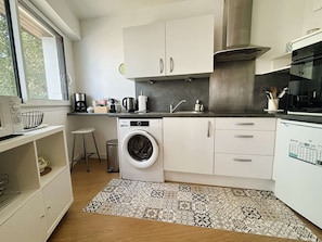 A compact kitchen with a washing machine, a coffee maker, and a sink. - Bénodet, 3 stars apartment, beach, thalassotherapy and shops on foot (BENODET)