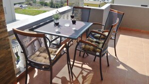 Un balcón con mesa y sillas, con vista a una masa de agua.