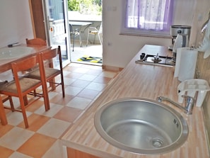 Cocina con lavabo, estufa y zona de comedor con sillas.