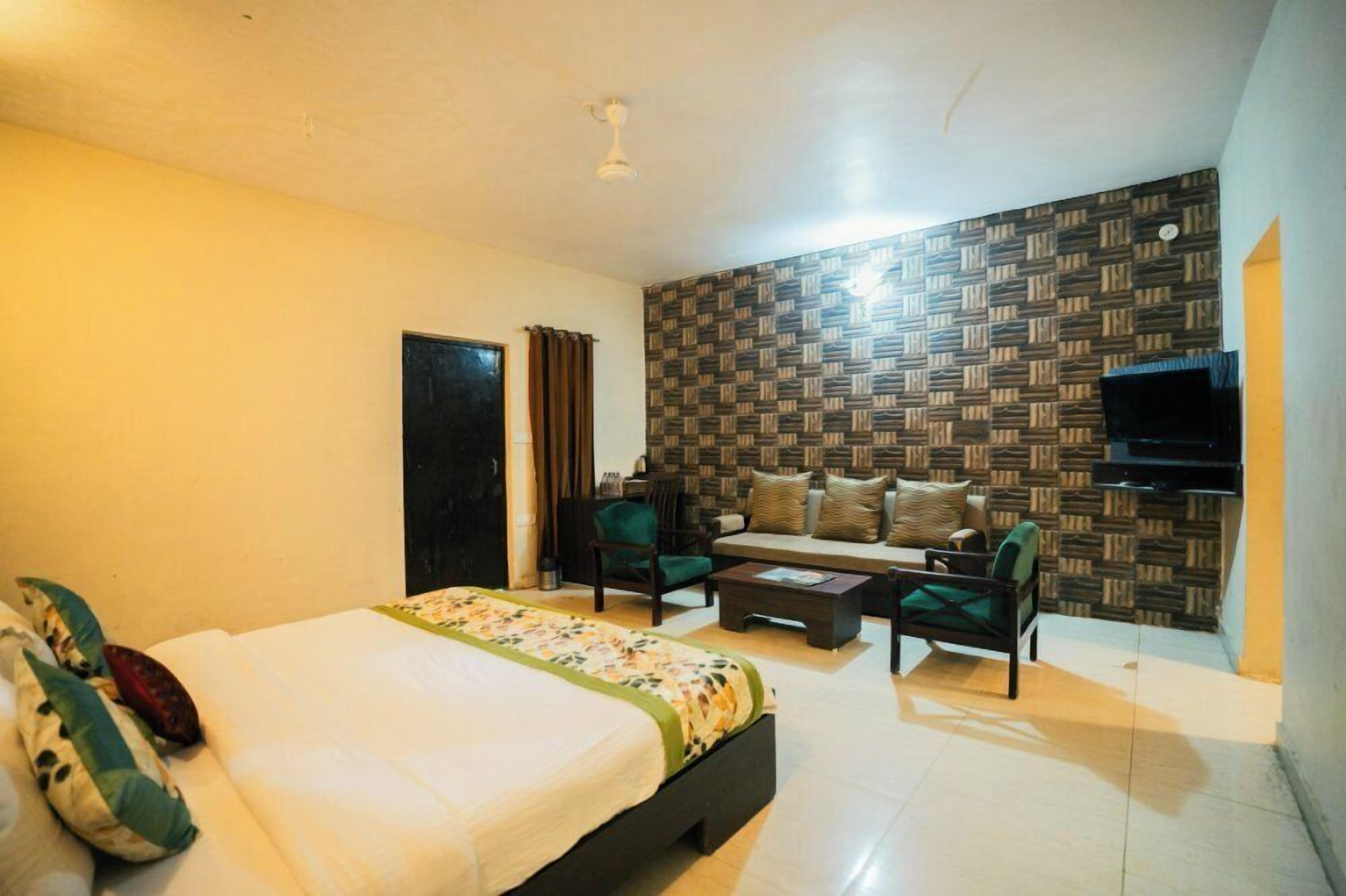 Habitación de hotel con cama, sofá, mesa de centro y televisor.