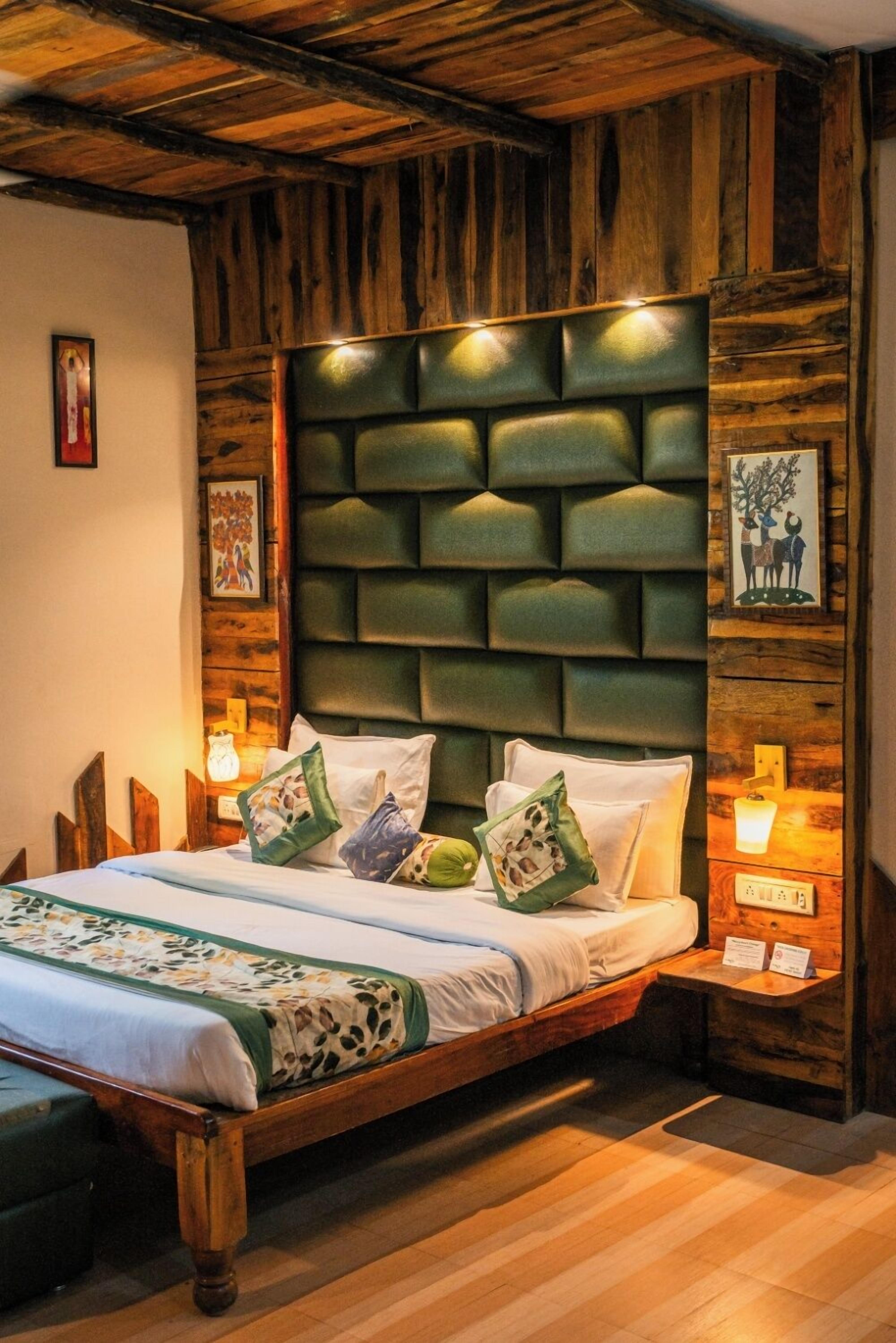 A wooden-framed bed with a padded headboard, multiple pillows, and bedside lamps.