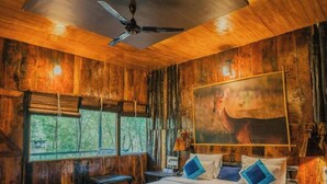 Un dormitorio de cabaña de madera con cama, ventilador de techo y un cuadro en la pared.