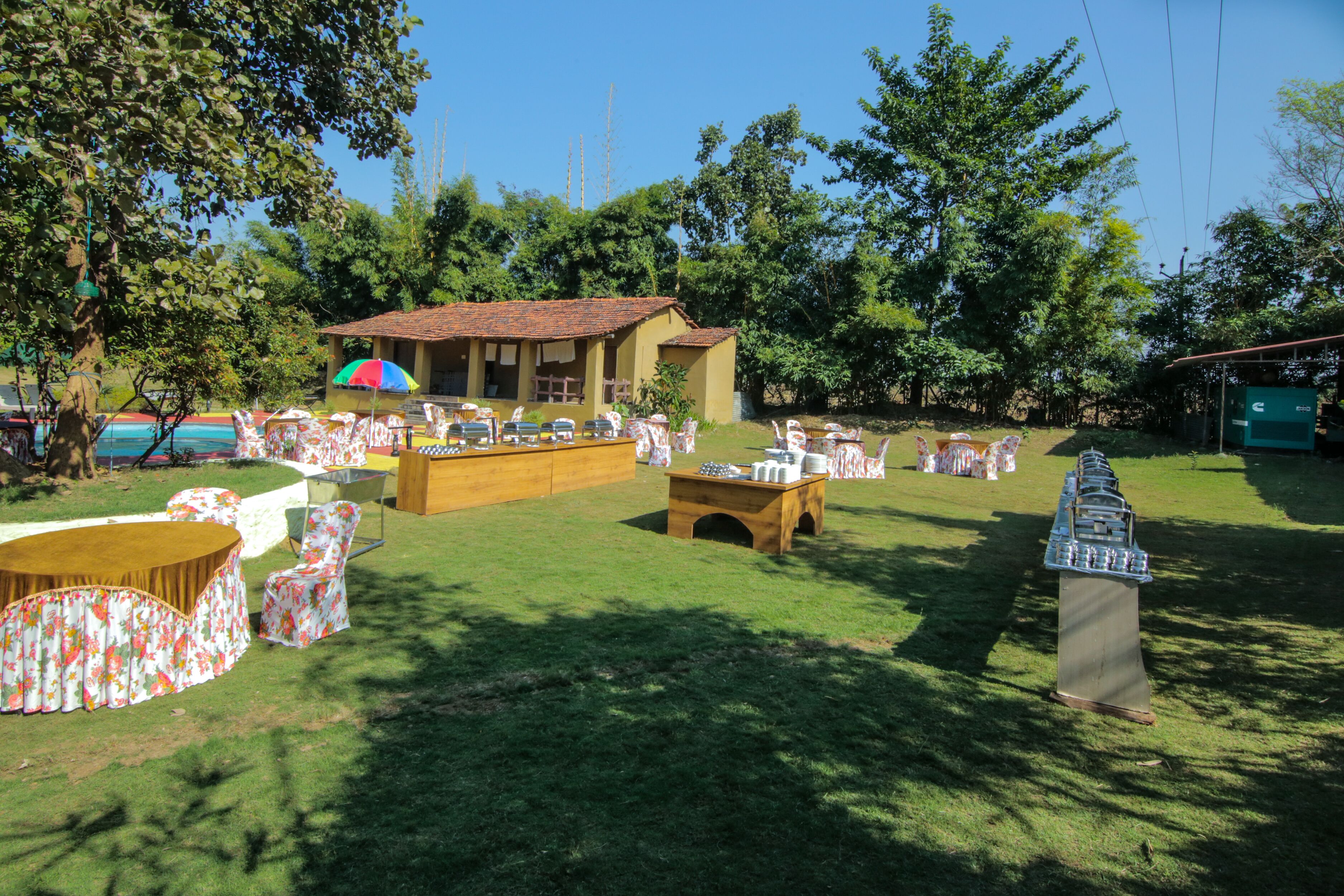 An outdoor event space with tables and chairs, a small building, and a large ship model.