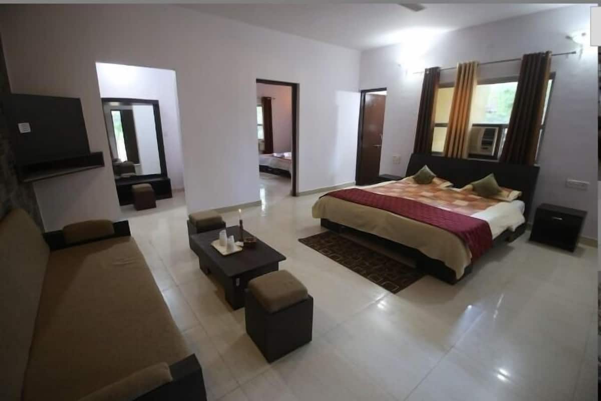 Una habitación de hotel con una cama, un sofá, una mesa de centro y un televisor.