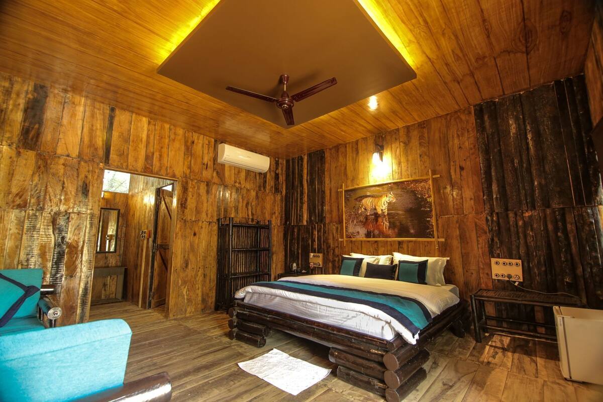 Una habitación rústica de madera con una cama, un ventilador de techo y una obra de arte con un tigre.