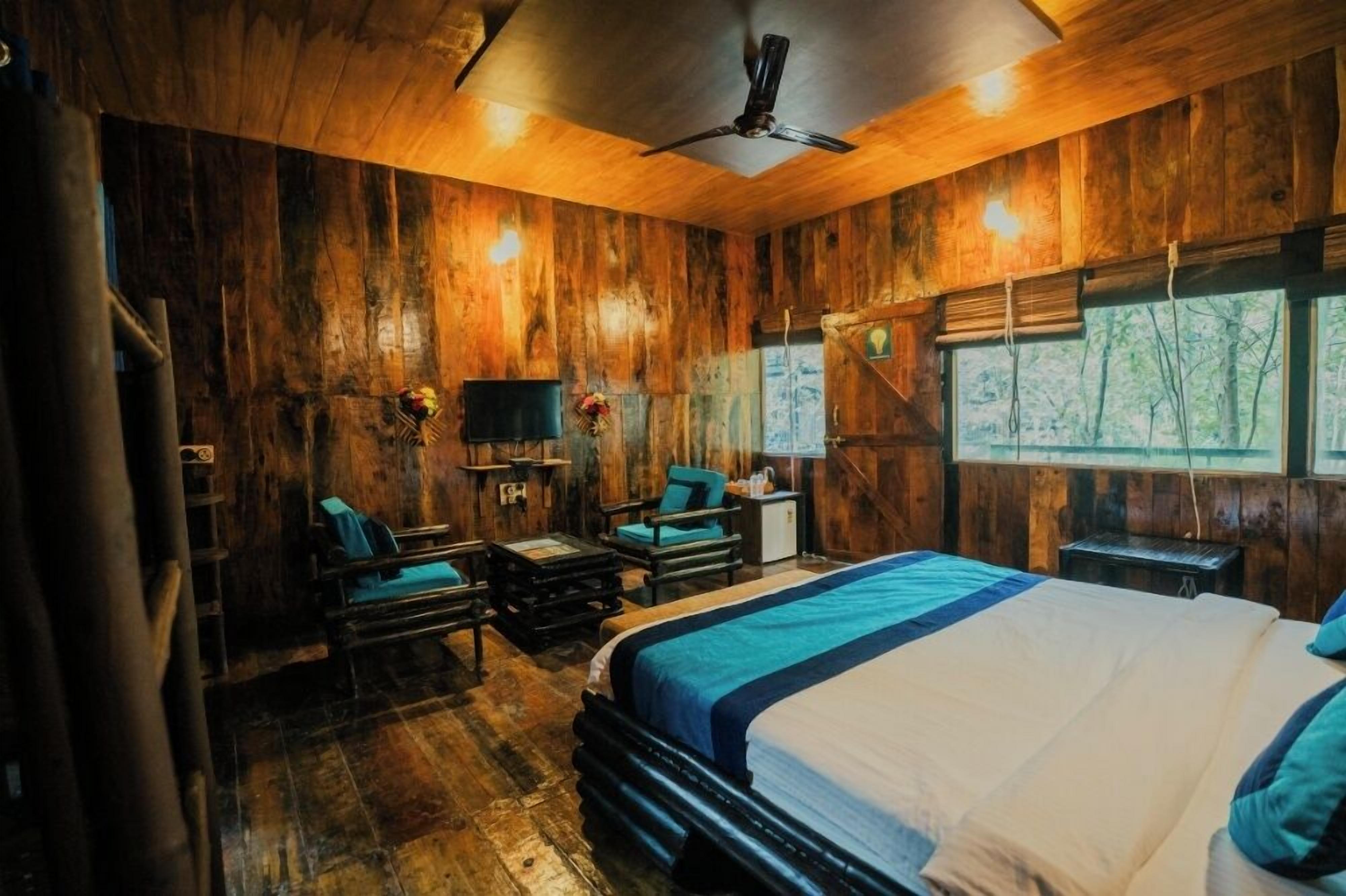 Una stanza in legno con un letto, due poltrone, un tavolino e una televisione.