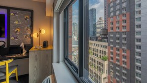A modern office space with a desk, chair, and large window offering a city view. - Pestana CR7 Times Square (New York)