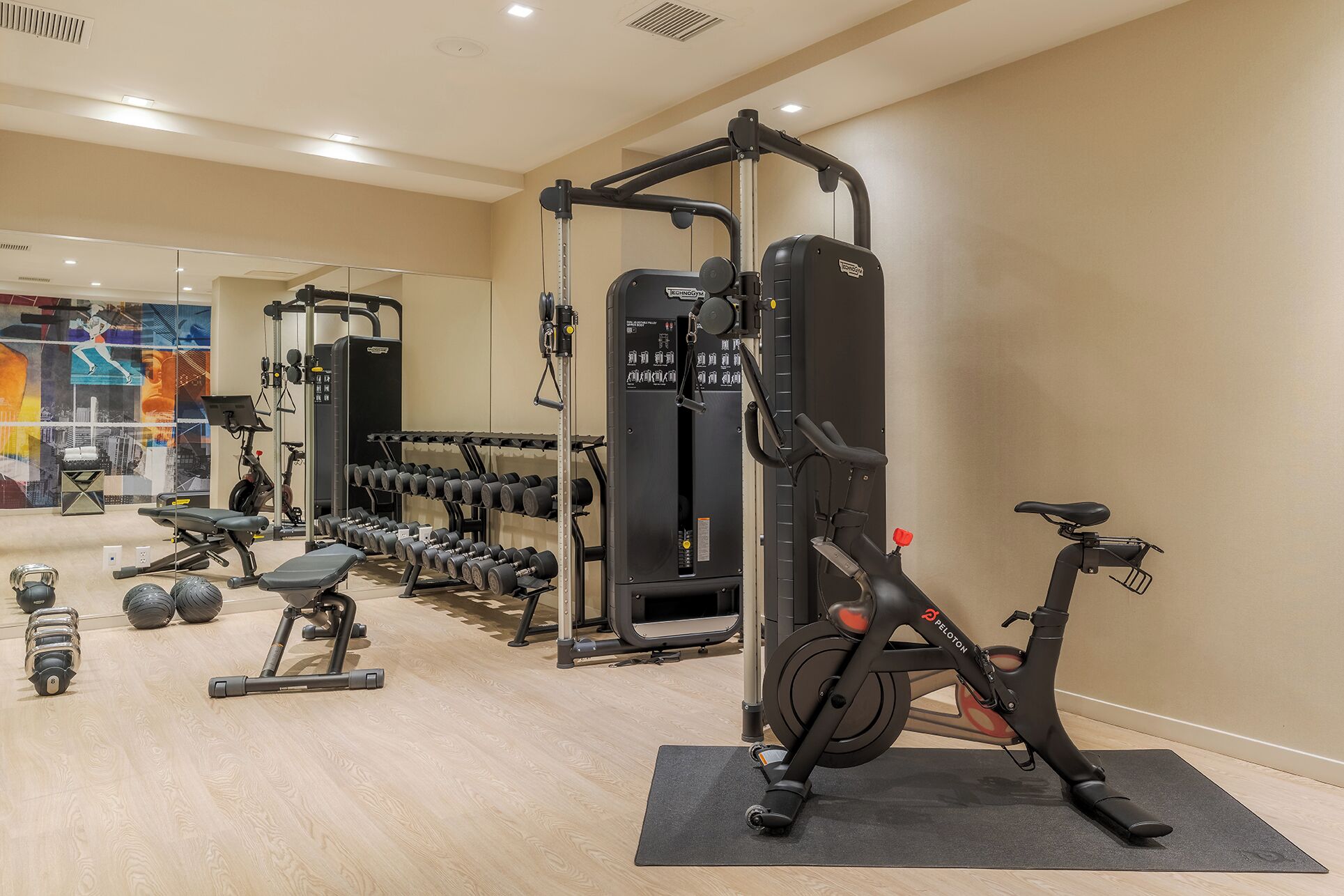 A gym with various exercise equipment, including dumbbells, a bench, and a Peloton bike.