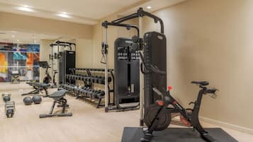 A gym with various exercise equipment, including dumbbells, a bench, and a Peloton bike.