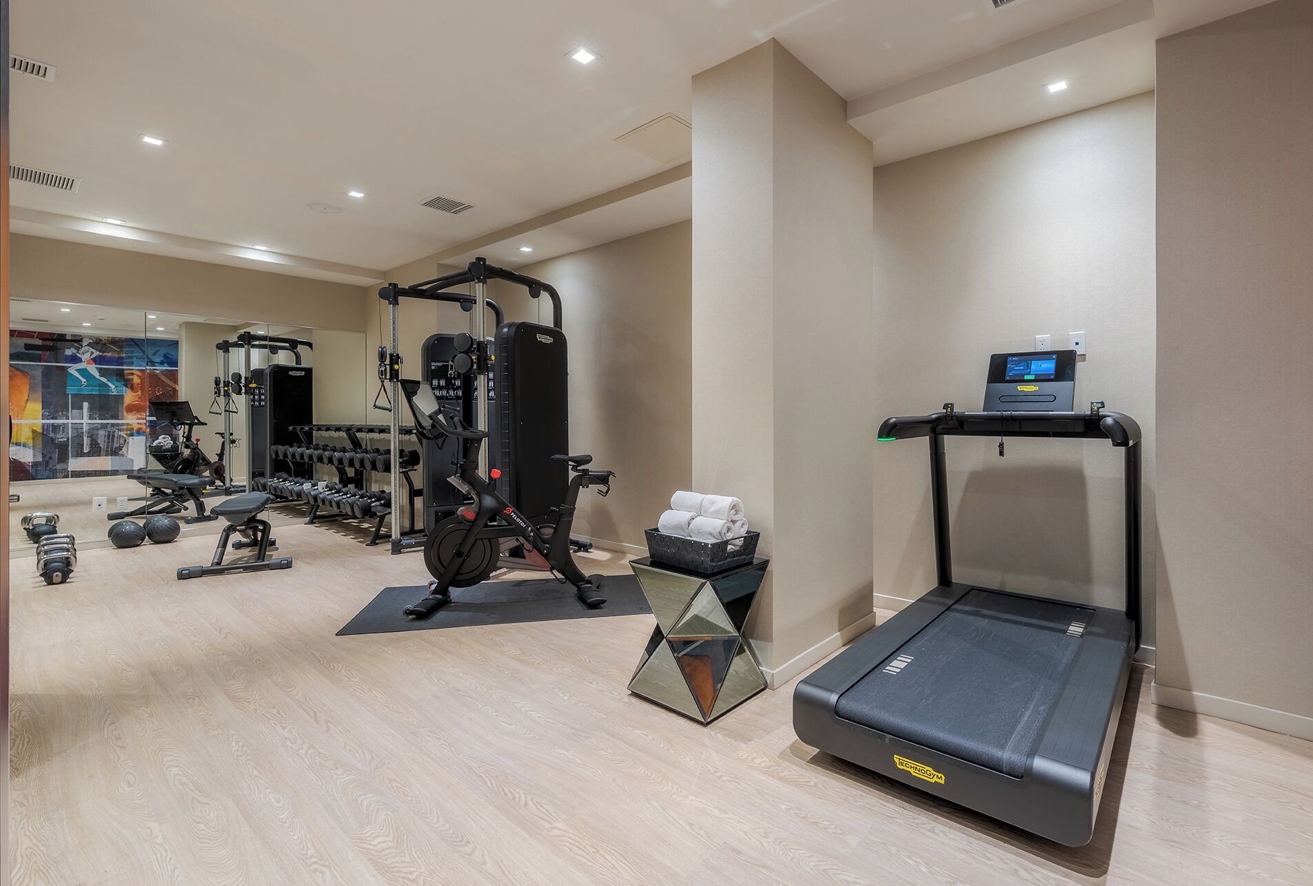 Un gimnasio moderno con equipo de ejercicio, una cinta de correr y una pantalla digital.