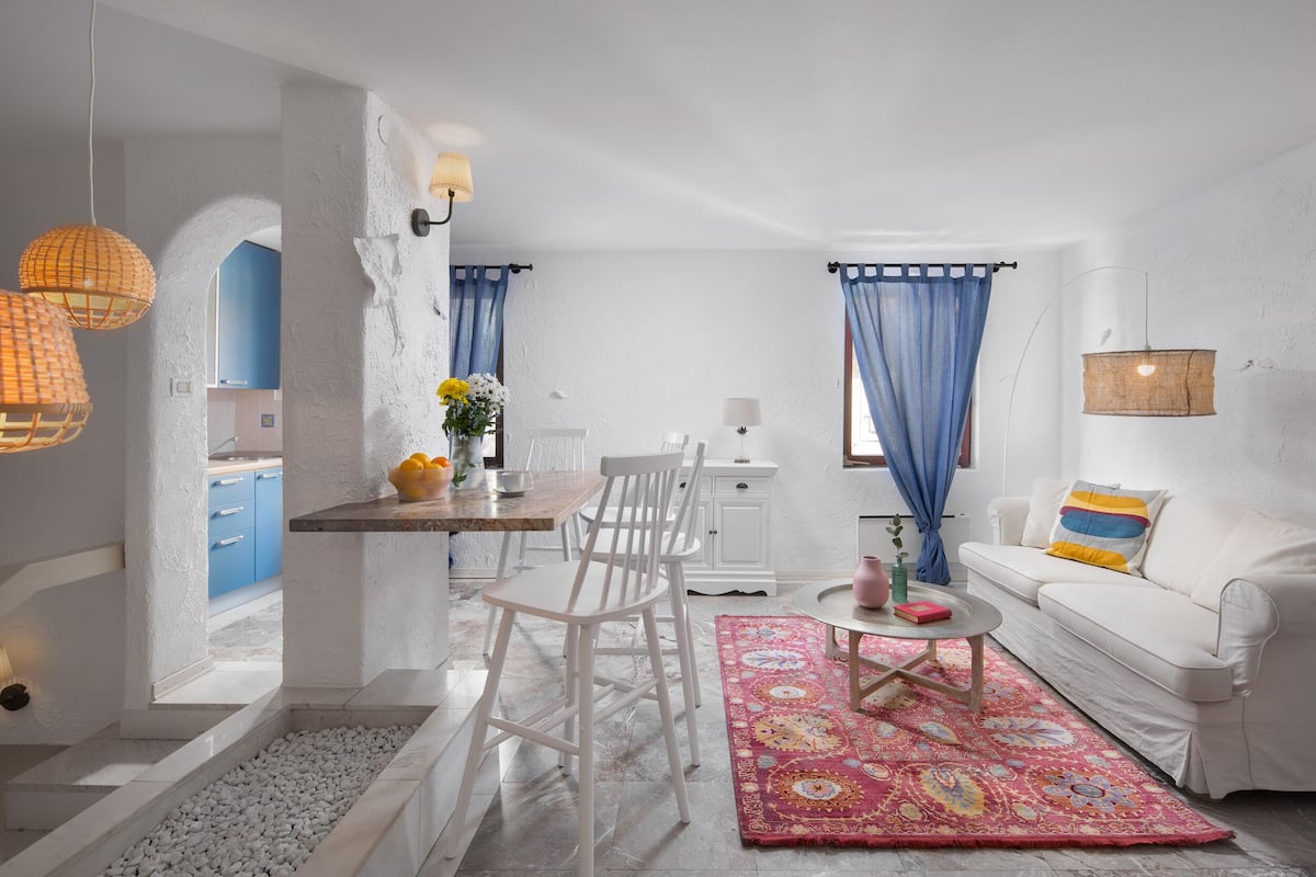 A compact living space with a dining area, a sofa, and a kitchen visible through an archway.