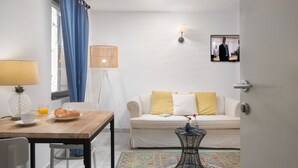 A living room with a wooden table, a white sofa, a patterned rug, and a television on the wall. - Villa Cissa Apartments by Irundo (Rovinj)