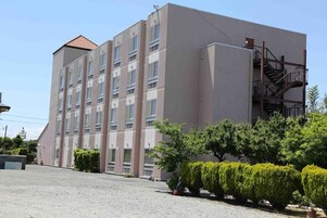 Un edificio de varios pisos con techo plano y una escalera de incendios en el lado derecho.
