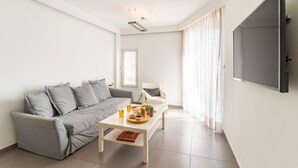 A modern living room with a grey sofa, a coffee table with a tray, and a flat-screen TV mounted on the wall. - Top Tier Apartment with Swimming Pool (Herzliya)