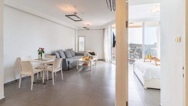 A modern living room with a dining area, a sofa, and a balcony with a city view. - Top Tier Apartment with Swimming Pool (Herzliya)