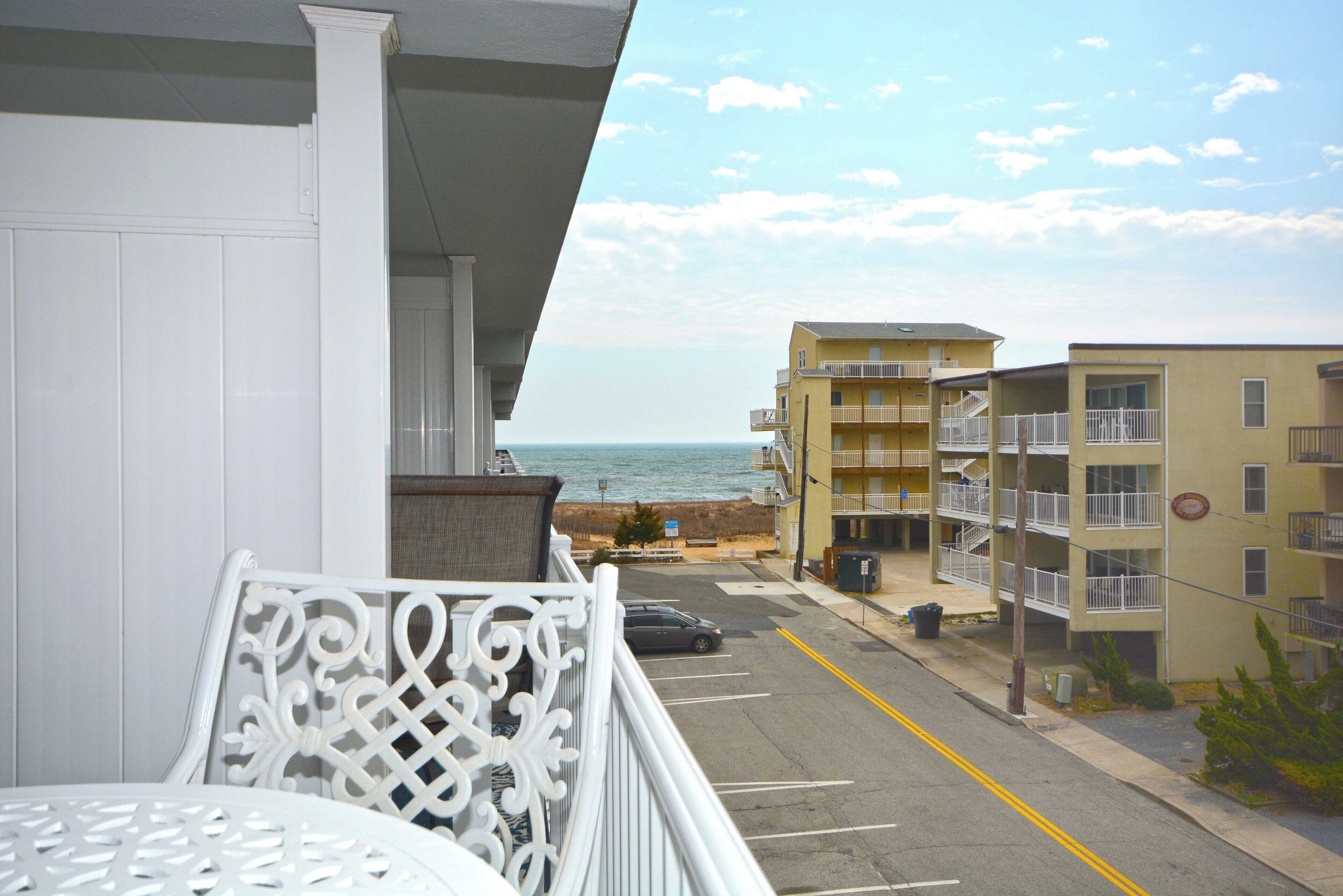 A balcony with a view of the ocean and adjacent buildings.