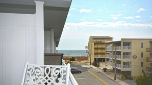 Un balcon avec vue sur l’océan et les bâtiments avoisinants.