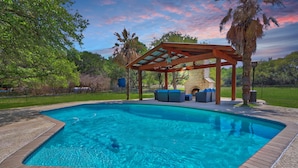 Ein rechteckiger Pool mit einer Holzpergola und Sitzgelegenheit.