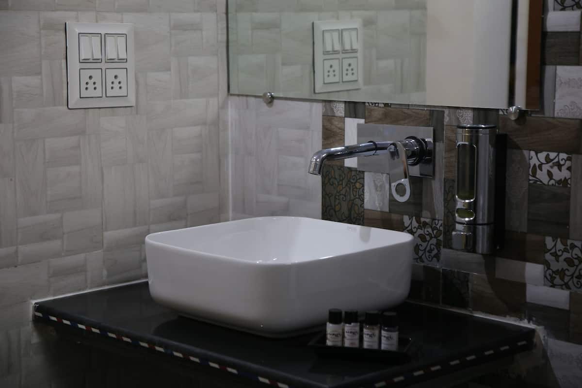 A bathroom with a white sink, a mirror, and a tiled backsplash.