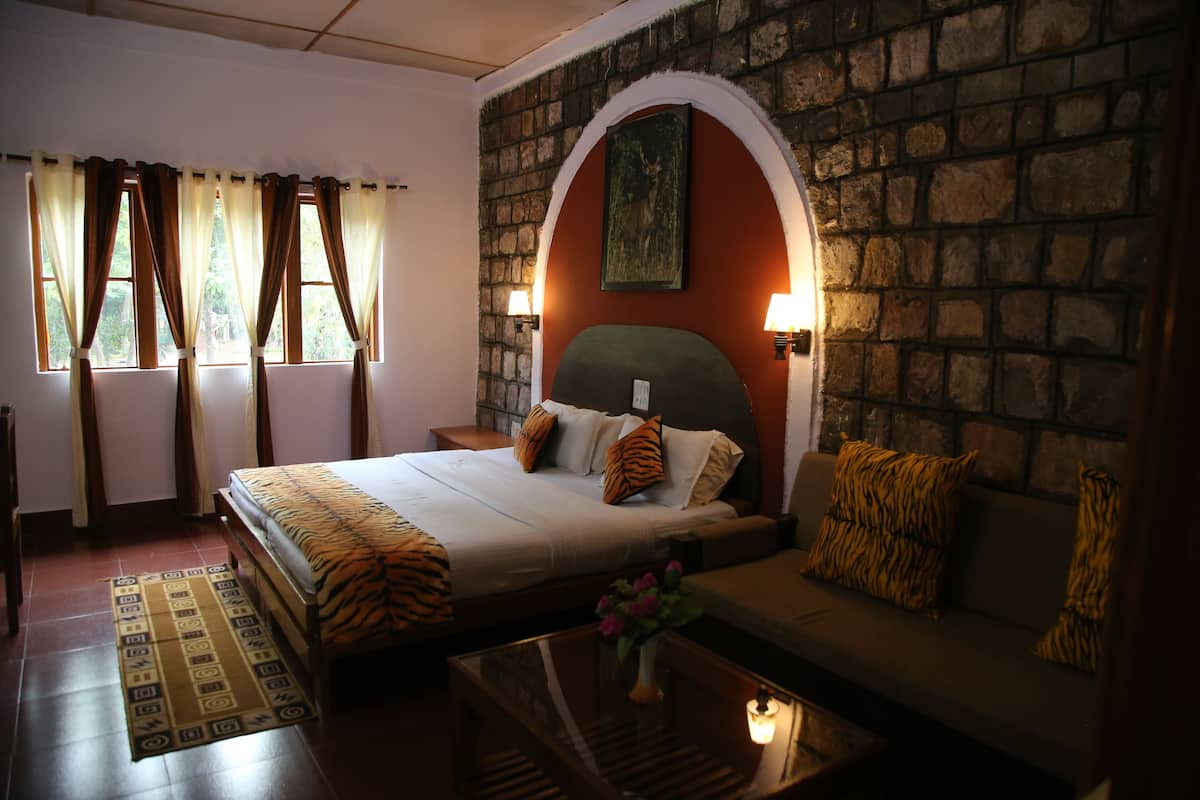 A bedroom with a bed, a sofa, a coffee table, and a rug.