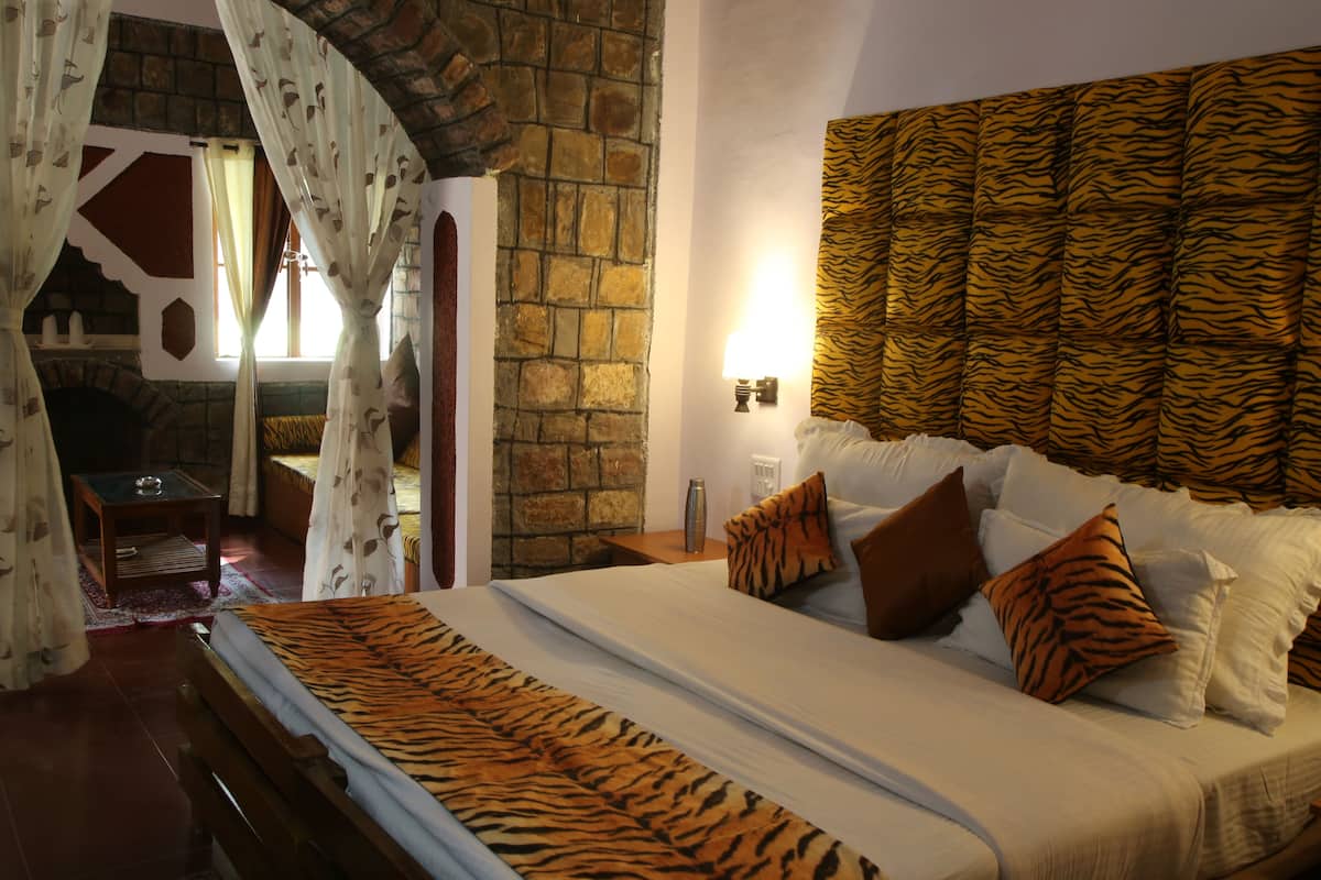 A bedroom with a stone wall, a bed with a tiger print bedspread, and a tiger print headboard.