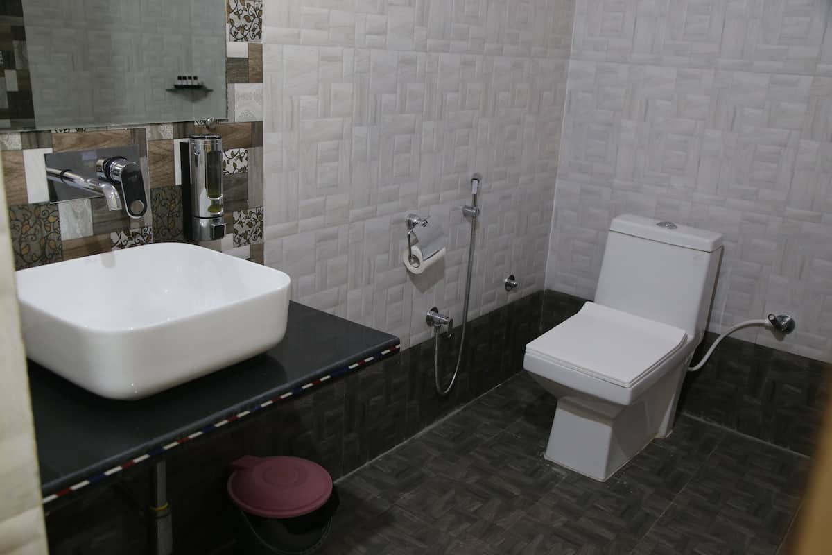 A bathroom with a white sink, a toilet, a shower, and a mirror.