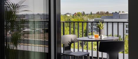 A balcony with two chairs, a table, and a potted plant.
