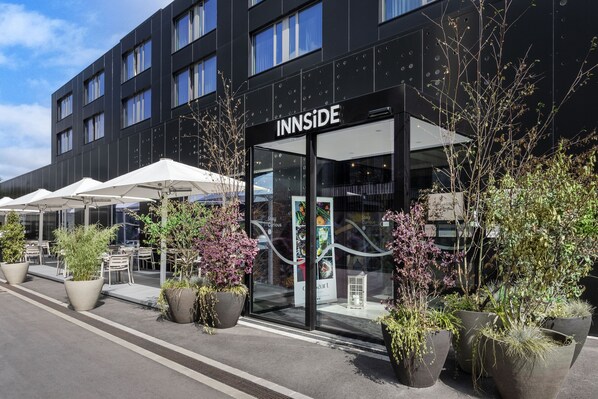 A modern building with the sign "INNSIDE" and outdoor seating with umbrellas.