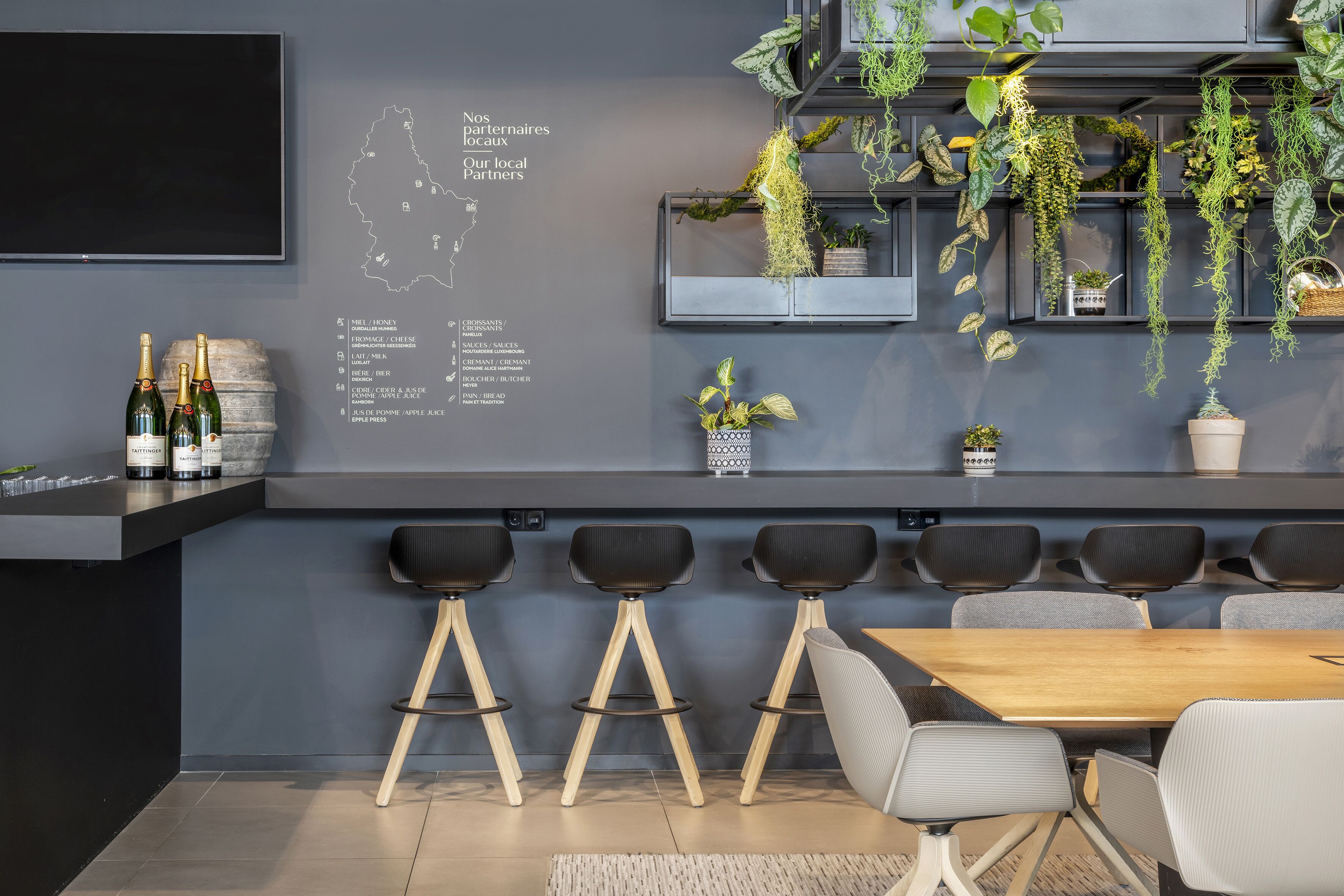 Une cuisine moderne avec un coin bar, des tabourets de bar, une table en bois et des plantes suspendues.