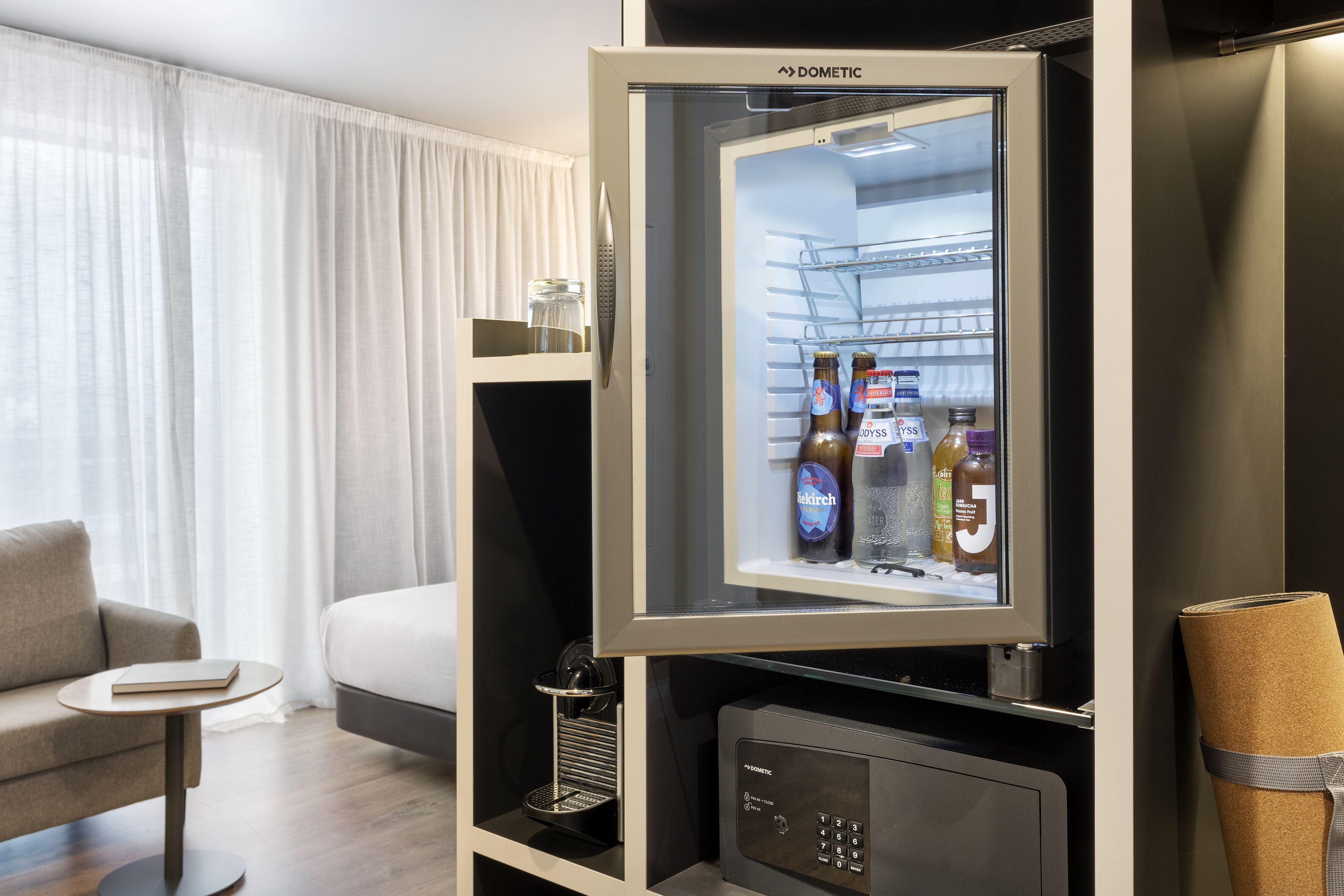 Ein Hotelzimmer mit Minibar, einem Bett, einer Couch und einem kleinen Tisch.