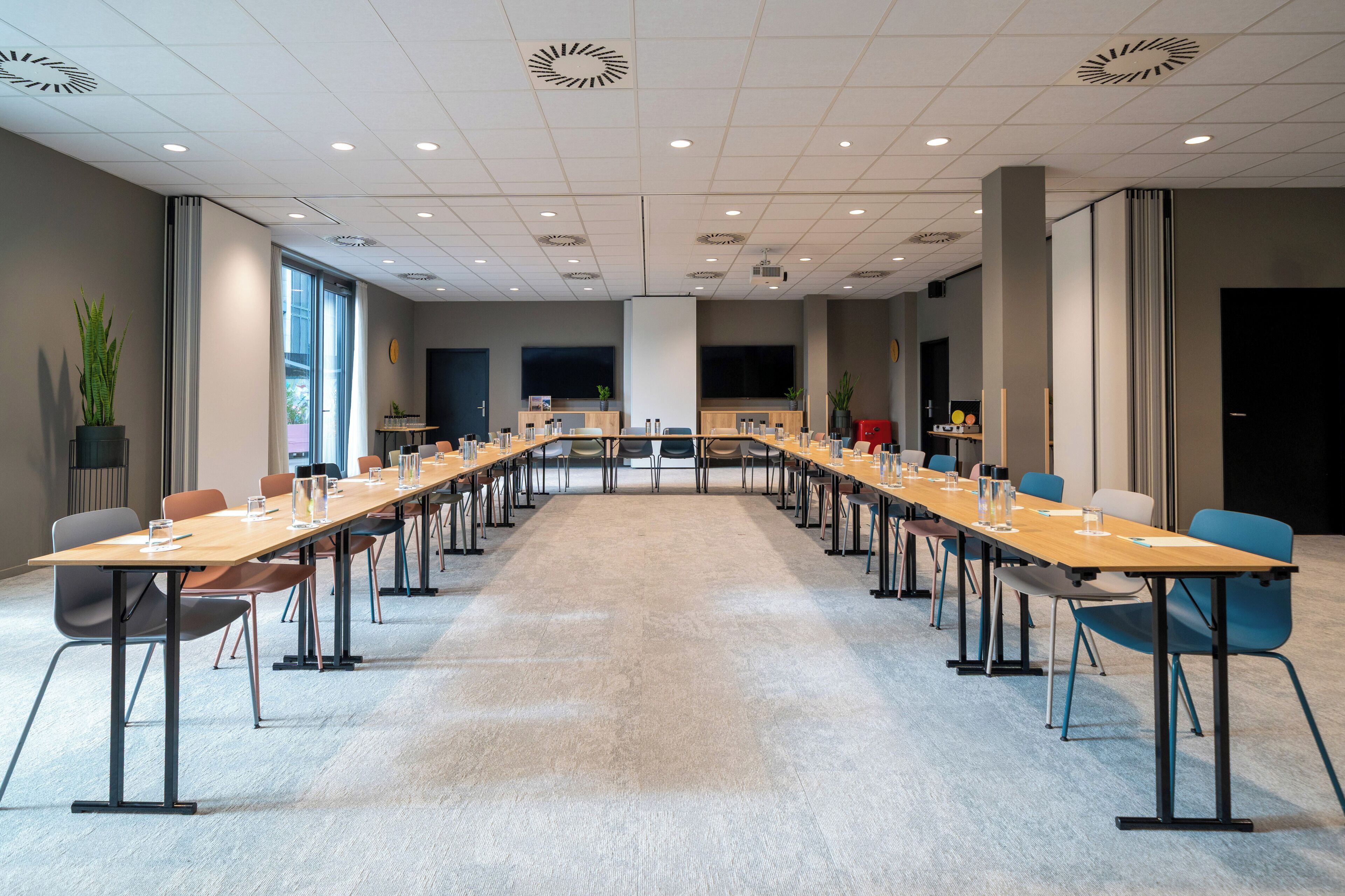 Un salón de conferencias con una mesa larga, sillas y una pantalla grande.
