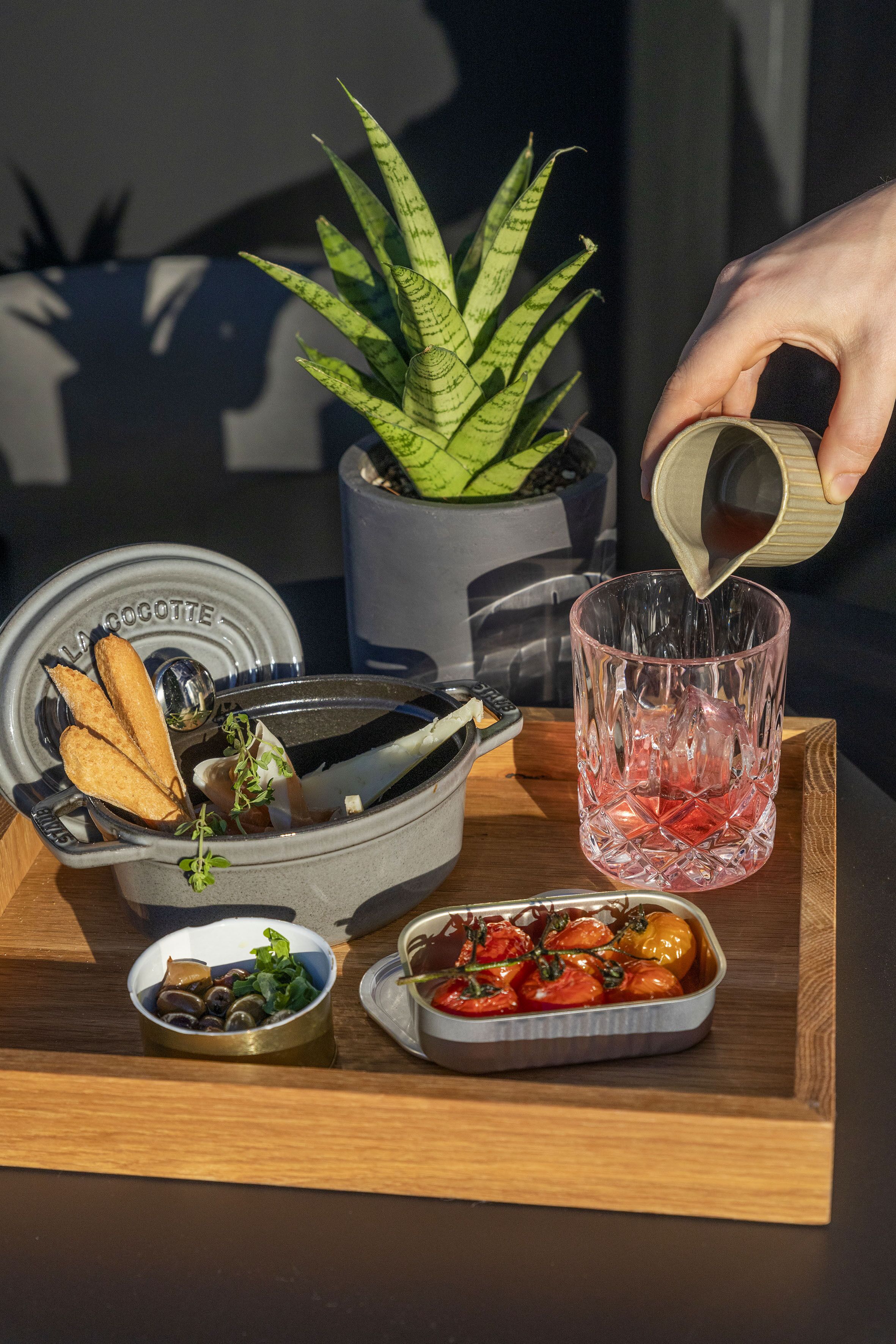 Una bandeja con un vaso, un bol de setas, un plato de tomates cherry y una planta en maceta.