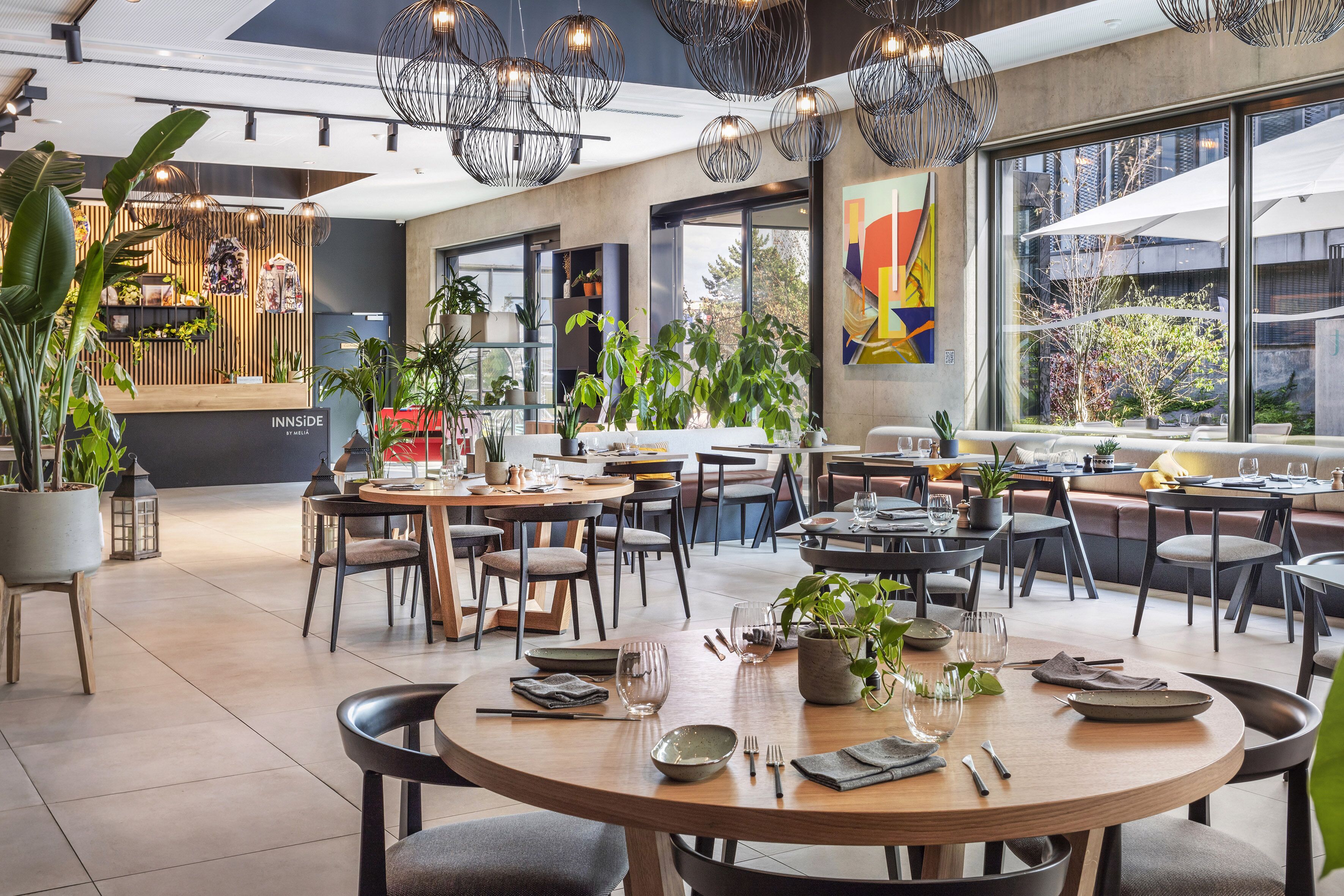 A modern dining area with round tables, chairs, and hanging pendant lights.