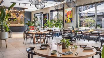 A modern dining area with round tables, chairs, and hanging pendant lights.