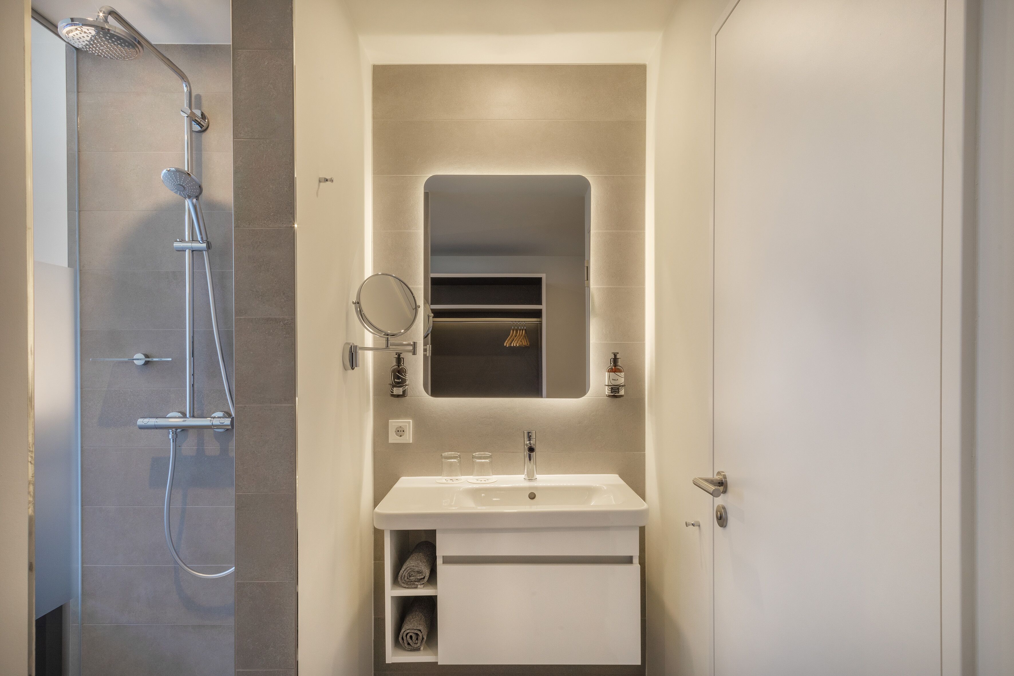 Un baño moderno con ducha, lavamanos y espejo.