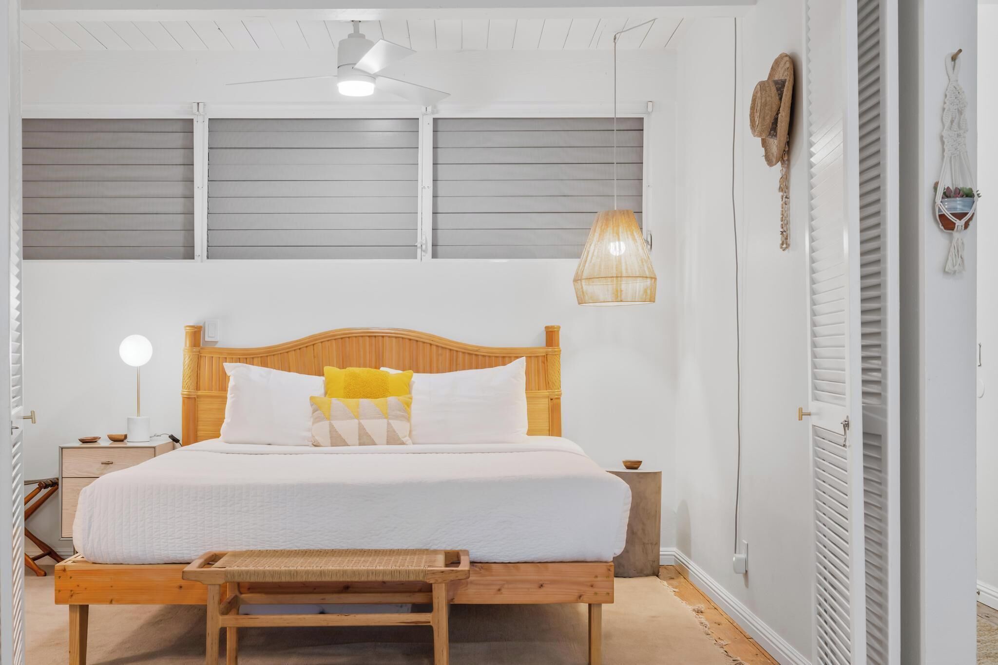 Un dormitorio con una cama de madera, una mesita de noche, una lámpara y una lámpara colgante.