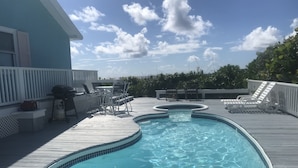A swimming pool with a wooden deck, lounge chairs, and a barbecue area. - South Beach: A Perfect Beachfront Getaway - Pool, beachfront, ocean views, (Hope Town Bahamas)