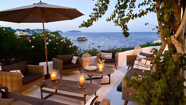 A terrace with wicker furniture, candles, and a view of the sea and boats. - Villa "La Quagliara" sea View (Ponza)