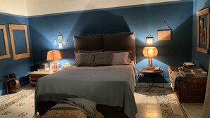A bedroom with a bed, two bedside tables, a lamp, a dresser, and a wall with framed pictures. - Villa "La Quagliara" sea View (Ponza)