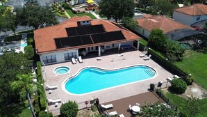 Une propriété résidentielle dotée d’une piscine, de chaises longues et d’un patio couvert.
