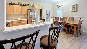 Une cuisine moderne avec des meubles en bois, un îlot central et un coin repas comprenant des chaises et une table en bois.