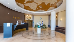 Un hall d’entrée avec un comptoir de réception, une horloge et des drapeaux.