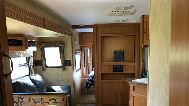 A compact RV interior with a kitchenette, a seating area, and a small window.