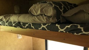 A bunk bed with patterned bedding and a window providing natural light.