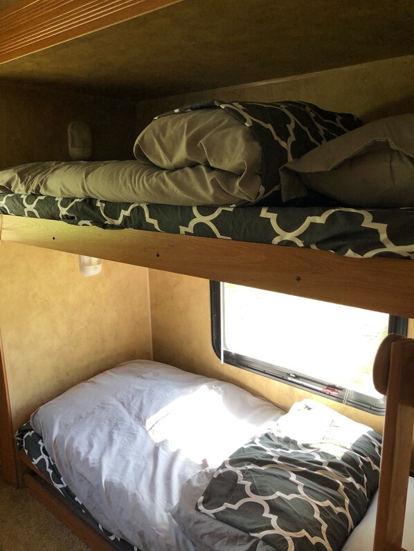 A bunk bed with patterned bedding and a window providing natural light.