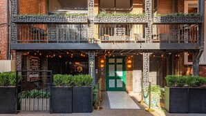 A two-story building with a green door, outdoor seating area with string lights, and a number '21' sign. - *Studio Loft*Walk to Broadway*Printers Alley Lofts (Nashville)