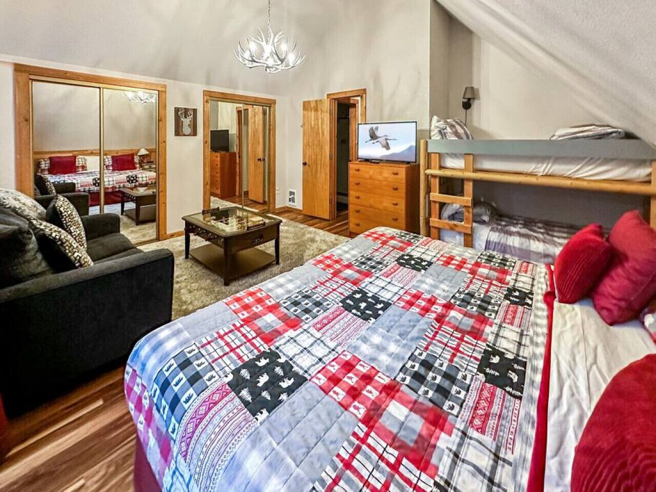 Une chambre à coucher avec un lit, une télévision, une commode et un miroir.