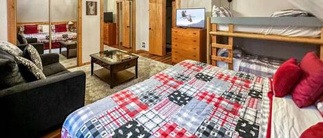 Une chambre à coucher avec un lit, une télévision, une commode et un miroir.